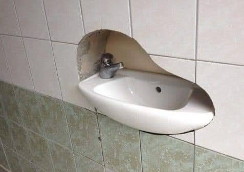 A tiled wall has a sink and its silhouette cutout. The sink was clearly there before the wall.