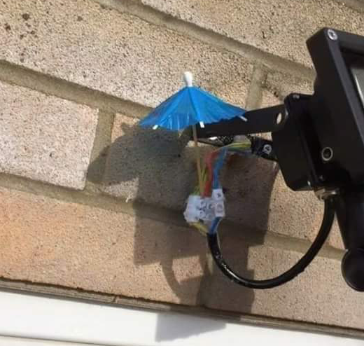 A small paper umbrella barely covers open electricity wires. It forms a hopeless shield against any rain.